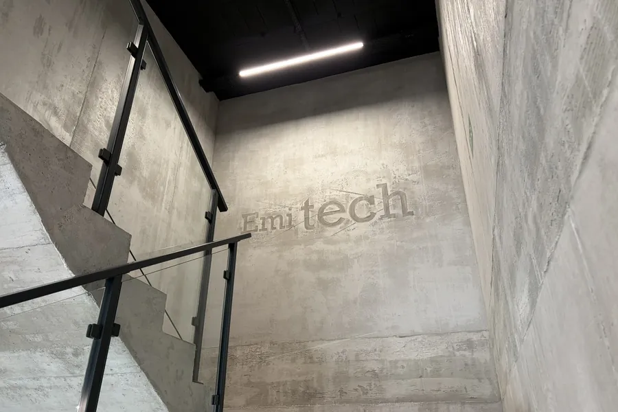 Klatka schodowa z logo Emitech na betonowej ścianie